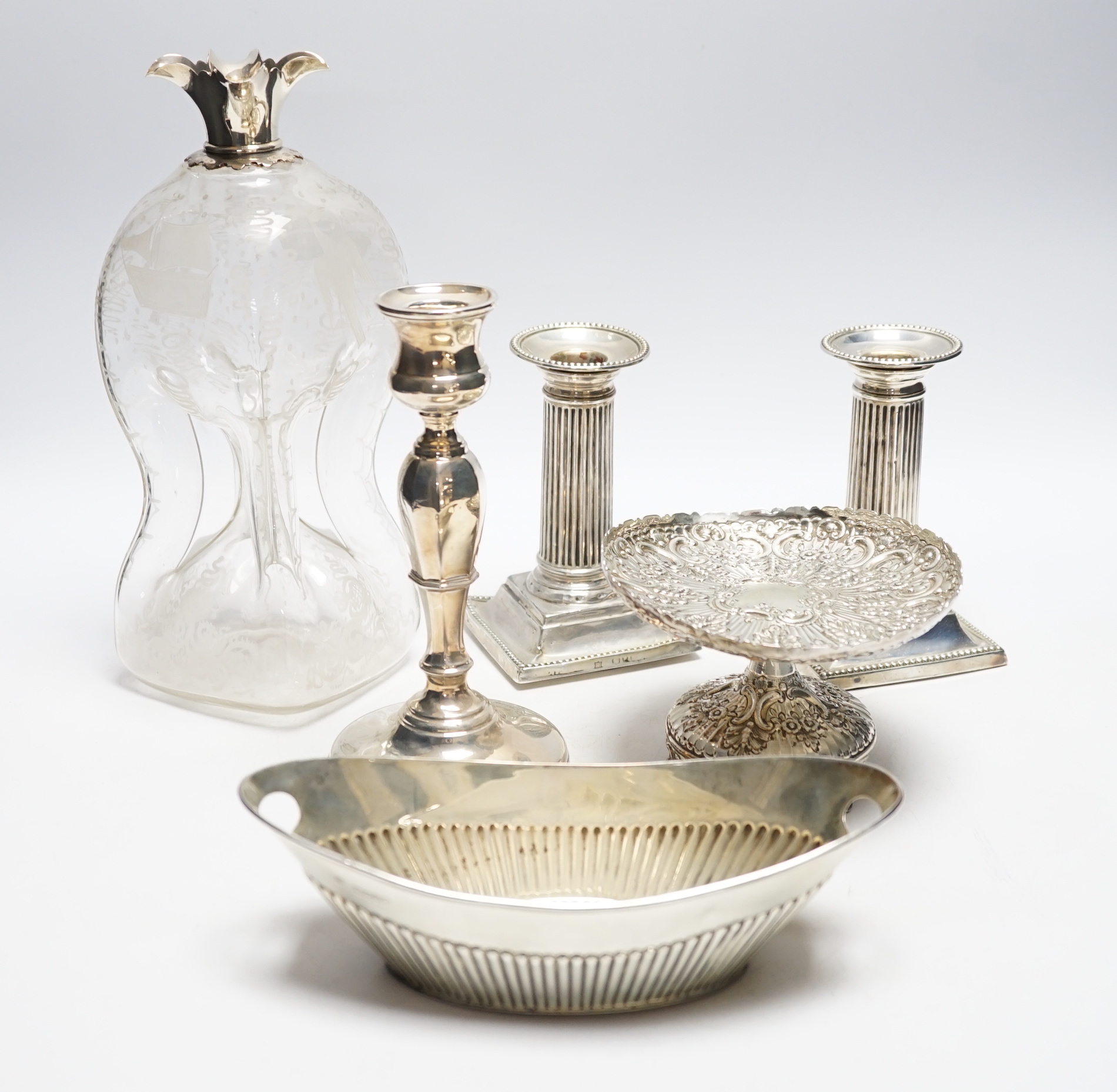 A pair of late Victorian silver mounted dwarf candlesticks, (a.f.)12.8cm, one other candlestick, a silver tazze, silver oval dish and a silver mounted glass decanter (lacking stopper).